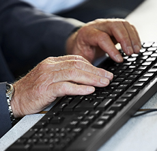 Senior executive working in office Closeup of senior businessman hands working on computer keyboard